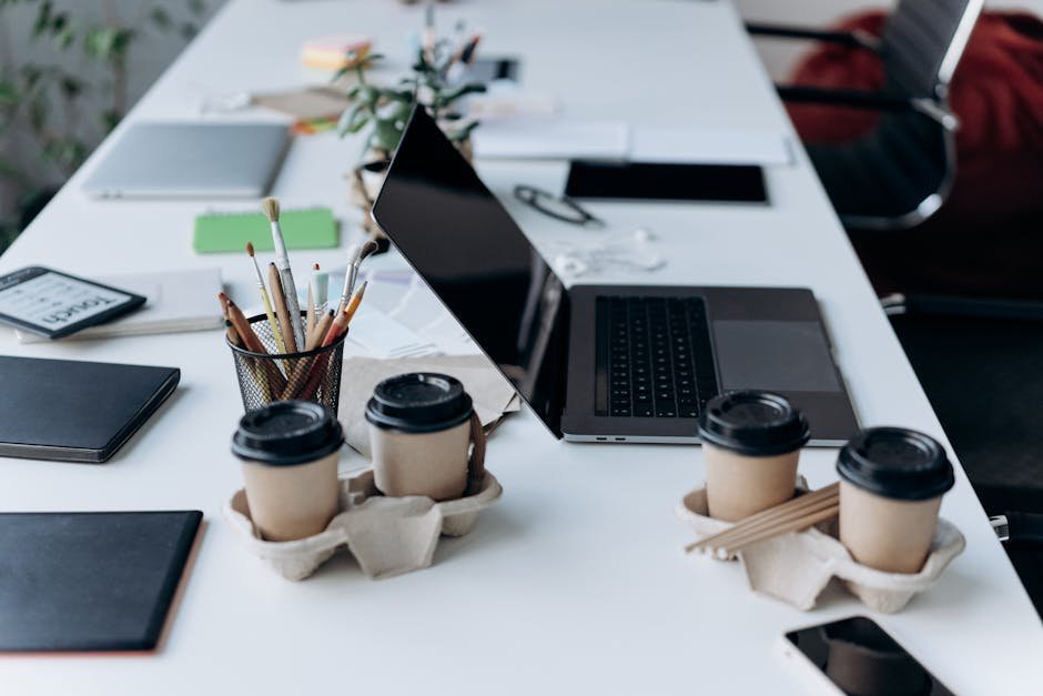 Multiple coffee cups arranged on a desk next to a laptop showing afternoon work fatigue