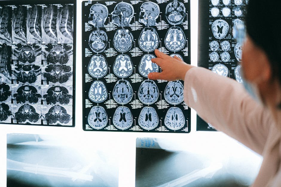 Brain MRI scans on a screen with neurologist reviewing, illustrating TBI evaluation context